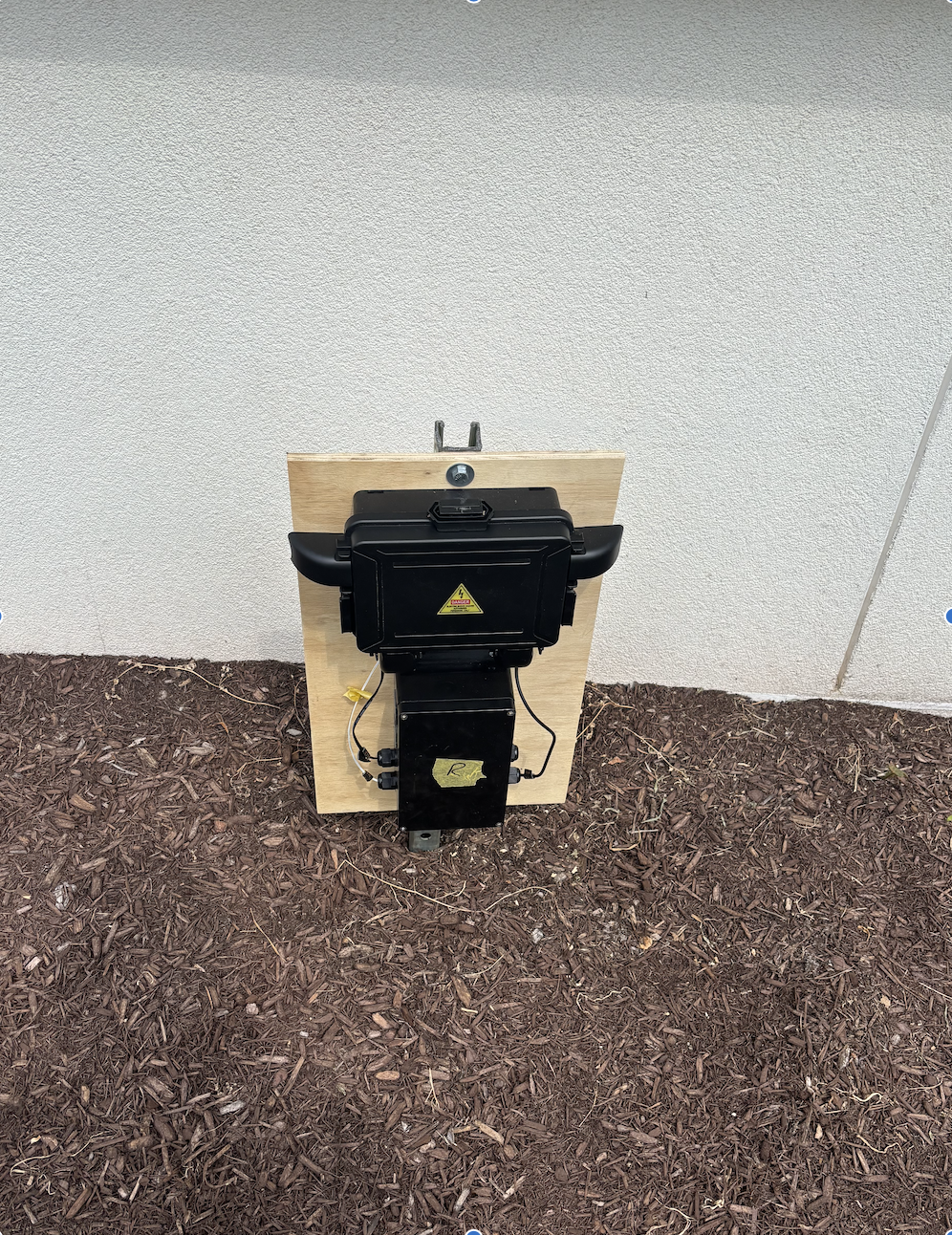 Outdoor installation with the Receiver ESP32 enclosure at the bottom and a waterproof outlet connector enclosure above, mounted on a wooden panel